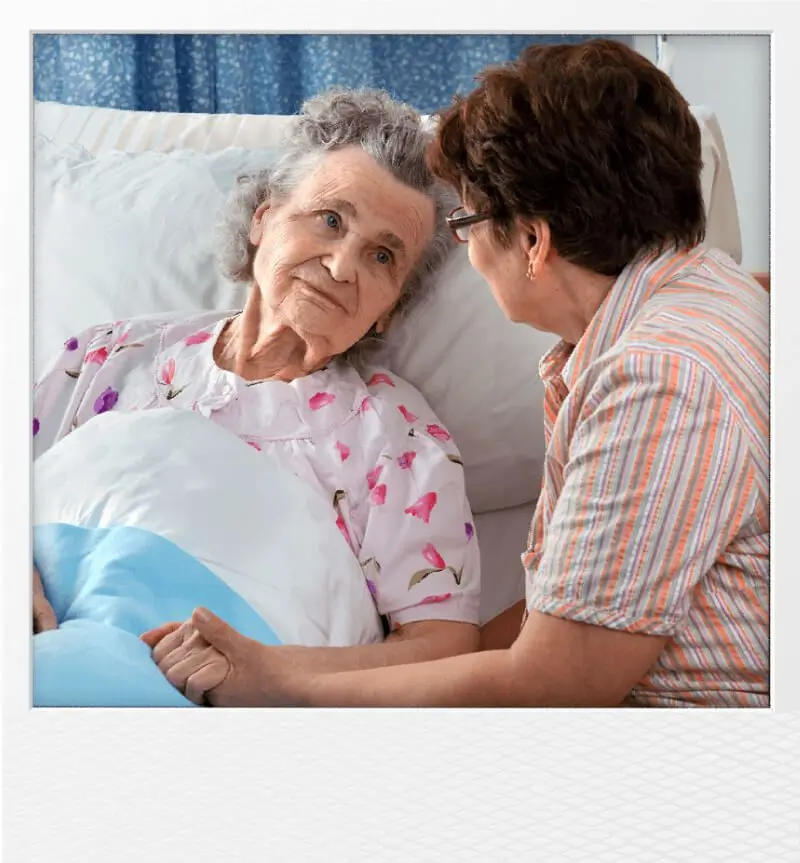 elderly women in bed with care assistant
